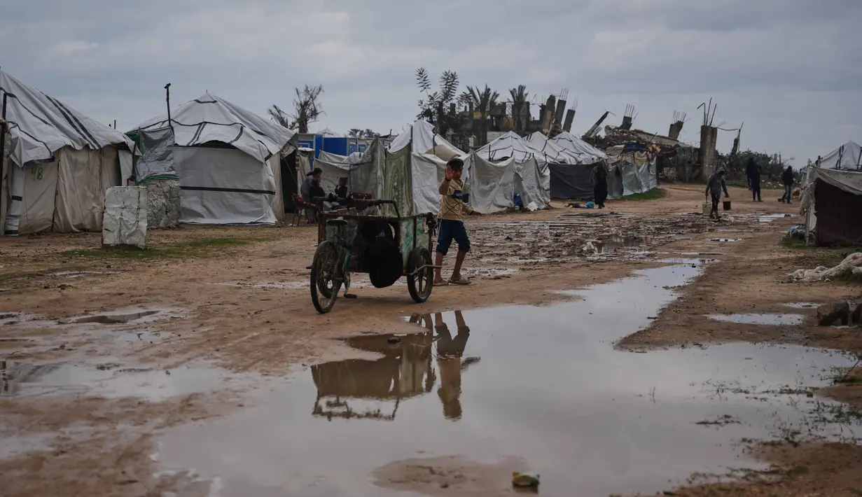 Sejak Desember 2025 hingga awal Januari 2026, dilaporkan sedikitnya 25 warga meninggal dunia terdampak cuaca ekstrem, termasuk anak-anak yang meninggal akibat hipotermia di kamp pengungsian. Tampak dalam foto, seorang anak berjalan di dalam kamp tenda untuk pengungsi Palestina setelah hujan deras di Nuseirat, Jalur Gaza tengah, Jumat, 2 Januari 2026. (AP Photo/Abdel Kareem Hana)