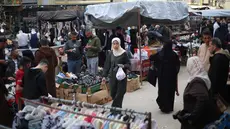 Warga Palestina yang mengungsi berbelanja di kios-kios pasar jalanan sekitar kamp pengungsi Nuseirat, Jalur Gaza tengah, pada Rabu 18 Maret 2026. Meski berada dalam situasi sulit dan di tengah reruntuhan, pasar jalanan sekitar kamp pengungsi Nuseirat, Jalur Gaza tengah, tetap ramai dikunjungi warga Palestina yang mengungsi. (Eyad Baba/AFP)