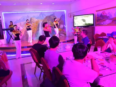 Sejumlah pengunjung menikmati hiburan di sebuah restoran Korea Utara, Pyongyang Okryu-gwan di Dubai (21/9). Restoran ini menyajikan berbagai makanan khas Korea Utara dan menghadirkan penampilan musik tradisional Korut. (AFP Photo/Giuseppe Cacace)