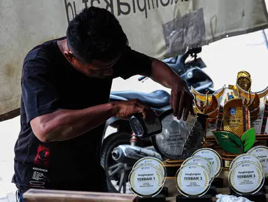 Pekerja menyelesaikan pembuatan plakat maupun piala untuk pemenang lomba di kawasan Ciledug, Kota Tangerang, Banten, Rabu (7/8/2024). (Liputan6.com/Angga Yuniar)