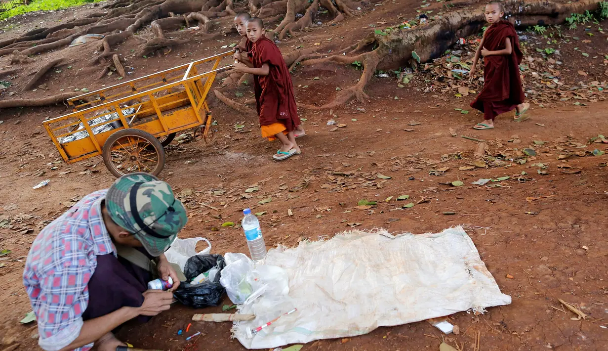 Sejumlah biksu Buddha melintas didekat pengguna narkoba di jalanan Man Sam, Myanmar, 11 Juli 2016. Sebanyak 42 ton sabu-sabu berhasil disita oleh kantor PBB untuk Narkoba dan Kejahatan (UNODC) pada 2013. (REUTERS/Soe Zeya Tun)