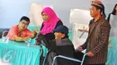 Warga disabilitas dibantu petugas KPPS berpakaian tradisional khas Jawa dan blangkon saat mengikuti pencoblosan Pilkada DKI 2017 di TPS tempat Presiden Jokowi menggunakan hak suaranya, TPS 04 Gambir, Jakarta Pusat, Rabu (15/2). (Liputan6.com/Angga Yuniar)