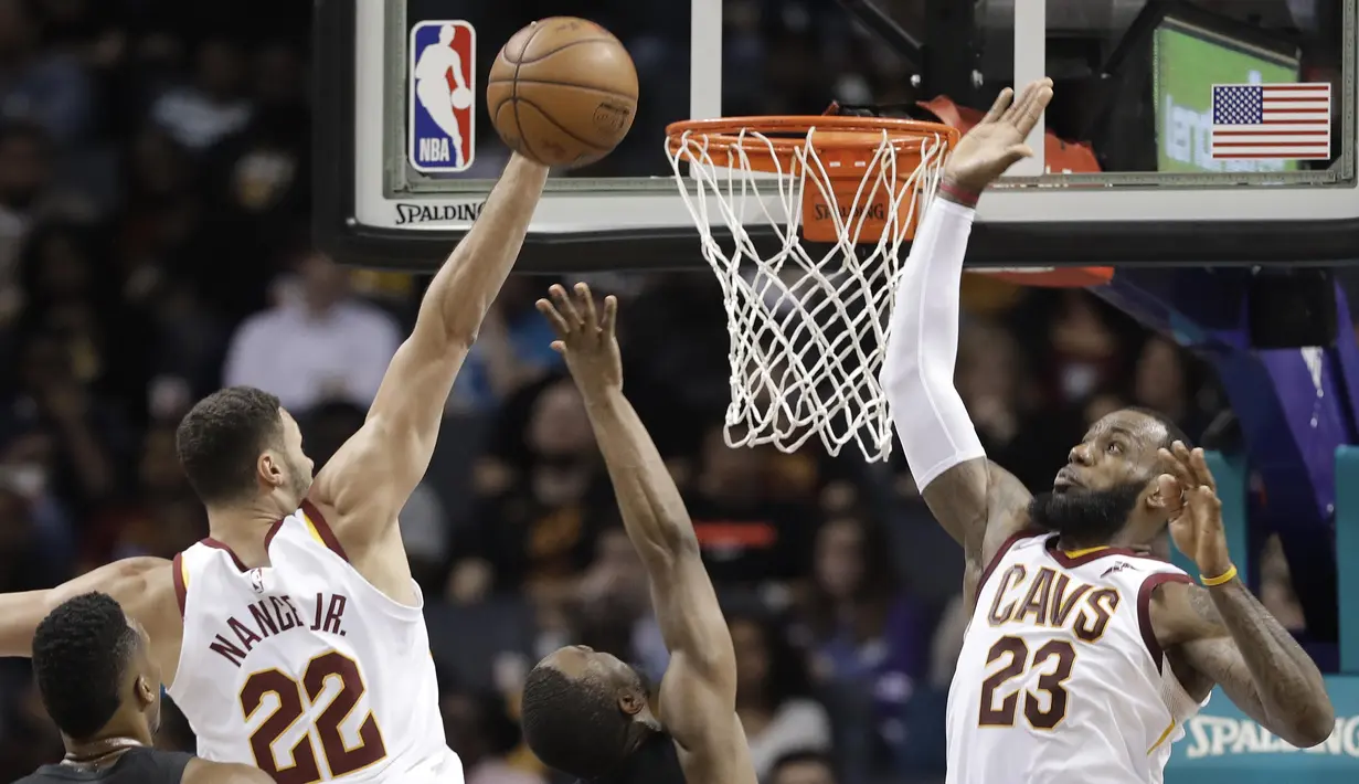 Pebasket Cleveland Cavaliers, LeBron James dan Larry Nance Jr, menghalau bola saat pertandingan melawan Charlotte Hornets pada laga NBA di Spectrum Center, Rabu (28/3/2018). Cleveland Cavaliers menang 118-105 atas Charlotte Hornets. (AP/Chuck Burton)