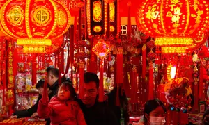 Orang-orang berbelanja dekorasi kemakmuran di sebuah stan untuk menyambut Tahun Baru Imlek, di sebuah Bazaar, Beijing, China, Minggu 1 Februari 2026. (AP Photo/Andy Wong)