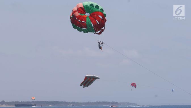 Wisatawan mengikuti permainan Parasailing di pantai Nusa Dua Bali, Rabu (10/10). Kementerian Pariwisata menyiapkan 63 paket wisata untuk turis yang berkunjung selama pertemuan IMF - Bank Dunia Bali 2018. (Liputan6.com/Angga Yuniar)