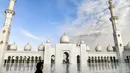 Seorang wanita melewati halaman Masjid Agung Sheikh Zayed di Abu Dhabi, Uni Emirat Arab. Masjid ini dibangun oleh presiden pertama Uni Emirat Arab, yaitu Sheikh Zayed bin Sultan Al Nahyan. (Photo by Vincenzo PINTO / AFP)