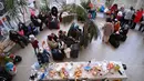 Relawan menyajikan makanan dan minuman untuk pengungsi Ukraina di pusat pengungsi sementara di sekolah dasar setempat di Tiszabecs, Hungaria timur, 28 Februari 2022. Warga Hungaria bergegas ke perbatasan Ukraina untuk membantu pengungsi yang melarikan diri dari invasi Rusia. (Attila KISBENEDEK/AFP)