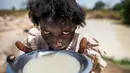 Seorang wanita bernama Alissa Lual minum air dari sebuah kubangan di lokasi proyek pembangunan jalan di dekat penampungan, Sudan Selatan (22/11). (AFP Photo/Albert Gonzalez Farran)
