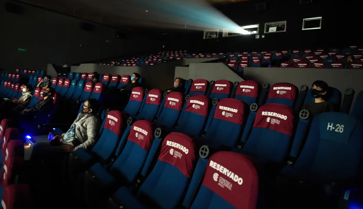 Orang-orang yang memakai masker menonton film di bioskop Cineteca Nacional saat pelonggaran pembatasan di Mexico City, Rabu (12/8/2020). Setelah ditutup hampir lima bulan akibat Corona, bioskop di ibu kota Meksiko dibuka kembali dengan kapasitas 30 persen. (ALFREDO ESTRELLA/AFP)