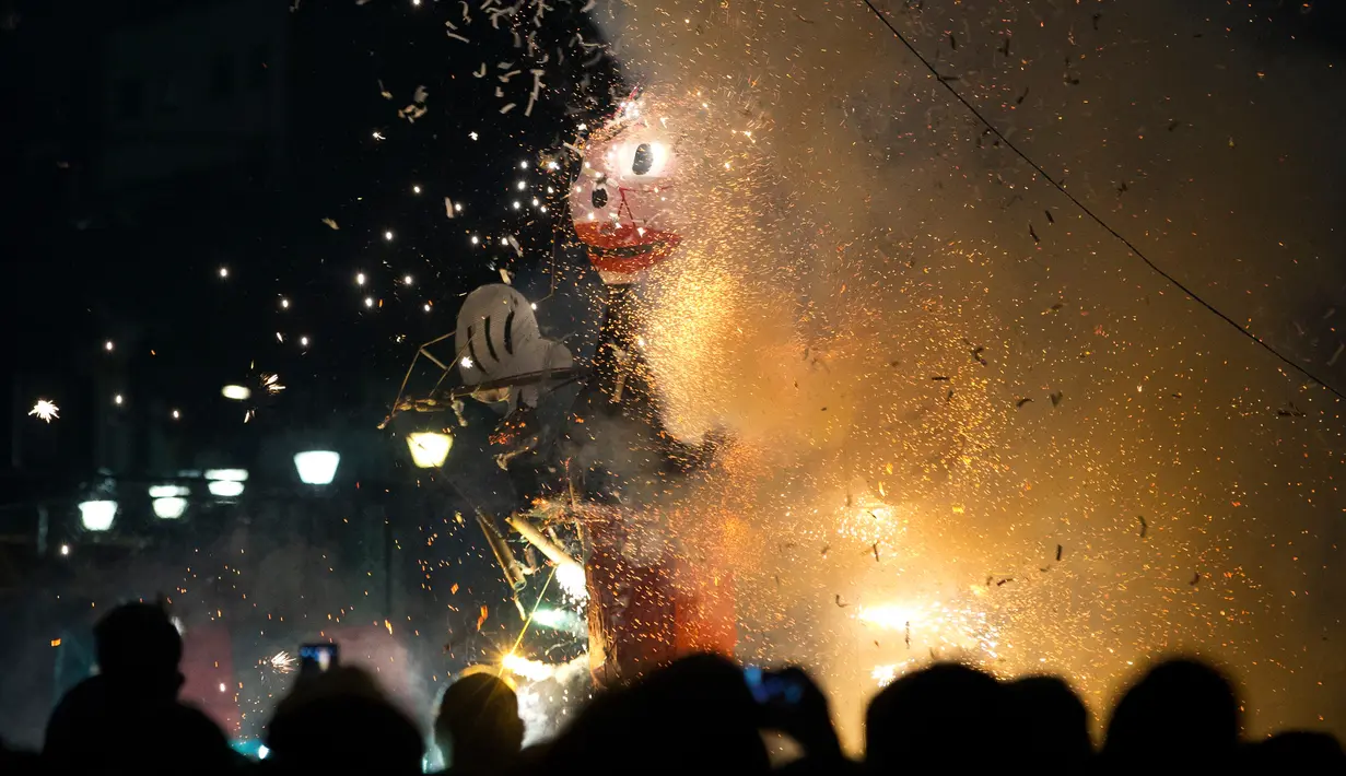 Warga menonton karakter Mickey Mouse yang saat perayaan pembakaran Yudas di Mexico City, Meksiko (15/4). Pembakaran adalah bagian dari tradisi Meksiko dalam Minggu Suci Paskah. (AP Photo/Rebecca Blackwell)