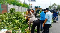 Personel Polsek Tampan Pekanbaru mengangkut tumpukan sampah di sebuah ruas jalan. (Liputan6.com/M Syukur)