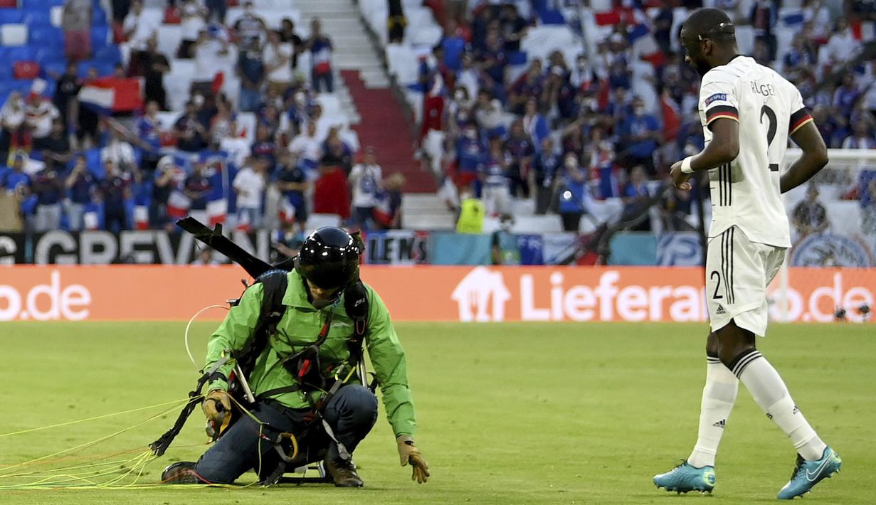 Akhirnya aktivis tersebut mendarat dengan selamat diposisi yang berdekatan dengan pemain Timnas Jerman, Antonio Rudiger. (Foto: AP/Pool/Matthias Hangst)