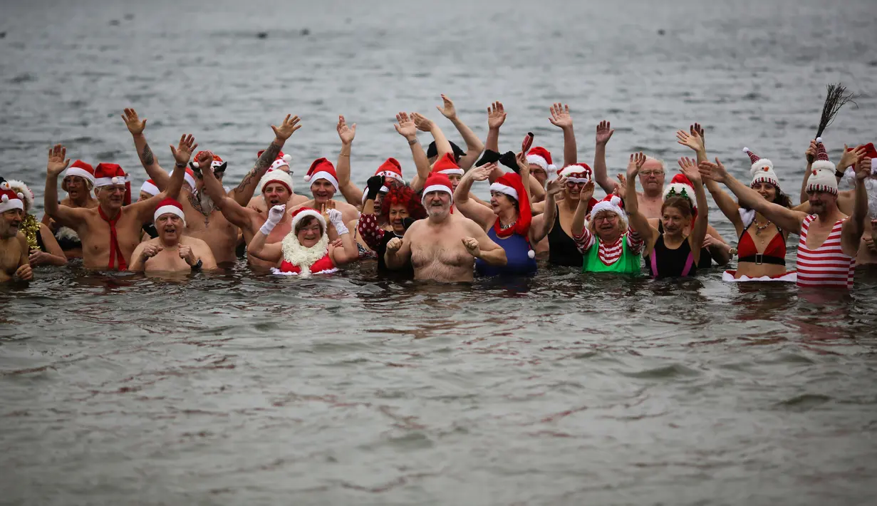 Anggota klub renang "Berliner Seehunde" (Berlin Seals mengenakan topi bertema Natal saat berenang di Danau Orankesee, Berlin yang dingin, Senin (25/12). Berenang di danau itu salah satu tradisi di Berlin menyambut Natal setiap tahun. (AP/Markus Schreiber)