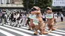 Aktivis kelompok hak hewan PETA mendesak orang untuk menjadi vegan selama protes di Tokyo, Jepang, Rabu (6/10/2021). Dalam aksinya, para aktivis mengenakan kostum dinosaurus. (CHARLY TRIBALLEAU/AFP)