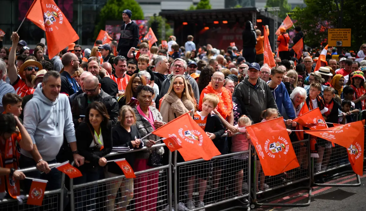 Pendukung Luton Town menyambut kedatangan parade bus timnya melewati jalanan di Luton, Inggris setelah berhasil promosi ke Liga Inggris musim 2023/2024 pada Senin (29/05/2023) waktu setempat. The Hatters sukses menyegel tiket promosi setelah memenangkan laga play-off divisi Championship melawan Covetry City 6-5 melalui adu penalti di Wembley, Sabtu (27/5/2023). (AFP/Daniel Leal)