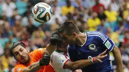 Penjaga gawang Iran, Alireza Haghighi (kiri), berusaha menahan sundulan kepala pemain depan Bosnia, Vedad Ibisevic, di laga penutup penyisihan Piala Dunia 2014 Grup F di Stadion Fonte Nova, Salvador, Brasil, (25/6/2014). (REUTERS/Sergio Perez)