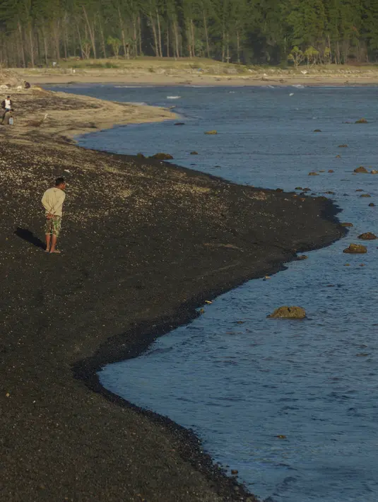 Pengunjung berjalan di pantai Lhoknga yang tercemar tumpahan batu bara dari kapal tongkang di Aceh, Rabu (1/8). Sekitar 7.000 ton batu bara tumpah dari kapal tongkang yang kandas dihantam gelombang sehingga merusak terumbu karang. (AFP/CHAIDEER MAHYUDDIN)