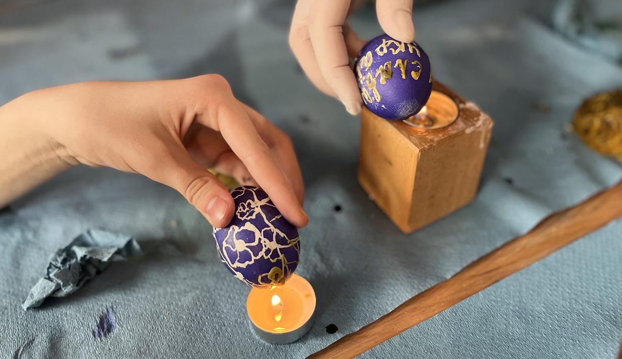 Wanita dan anak-anak Ukraina menghias telur Paskah untuk tentara dalam restoran Georgia di Lviv, Ukraina, 20 April 2022. Lebih dari selusin wanita dan anak-anak menghias telur rebus dan es roti Paskah tradisional dengan warna kuning dan biru, warna bendera Ukraina. (Alice HACKMAN/AFP)