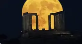 Bulan purnama terbesar atau supermoon muncul di belakang Kuil Poseidon di Tanjung Sounio, selatan Athena, Senin (19/8/2024). (AP Photo/Michael Varaklas)