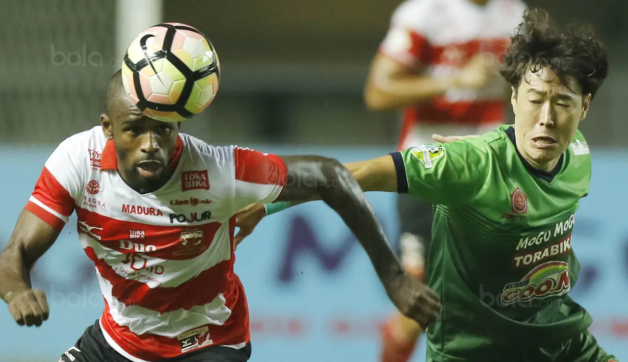 Striker Madura United, Greg Nwokolo, berebut bola dengan gelandang PS TNI, Soonhak Hong, pada laga Liga 1 Indonesia di Stadion Pakansari, Bogor, Senin (18/9/2017). Madura United menang 3-2 atas PS TNI. (Bola.com/M Iqbal Ichsan)