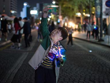 Seorang anak bersiap meluncurkan mainannya selama perayaan Chuseok di sebuah jalan di Seoul (5/10). Chuseok merupakan festival panen tahunan dan hari libur nasional selama seminggu di Korea Selatan. (AFP Photo/Ed Jones)