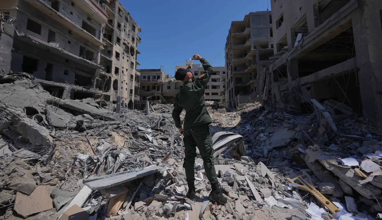 Seorang warga melemparkan puing-puing dari sebuah apartemen di sebuah gedung yang rusak akibat serangan Israel di kota pelabuhan Tyre, Lebanon Selatan, Kamis 18 Juni 2026. (AP Photo/Hassan Ammar)