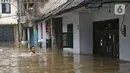 Warga berjalan menyusuri banjir di RW 07, Kelurahan Pekayon, Jakarta Timur, Sabtu (20/2/2021). Banjir di kawasan tersebut terjadi akibat curah hujan yang tinggi. (Liputan6.com/Herman Zakharia)
