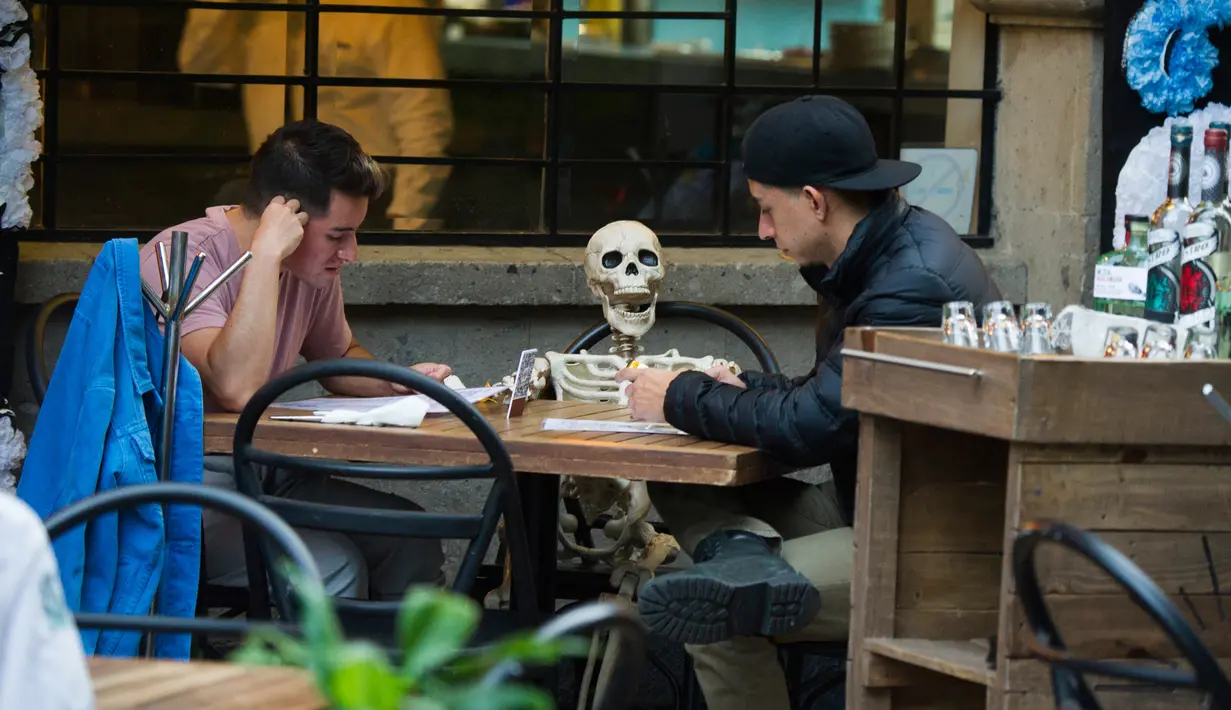 Pemandangan yang disebut Calaca (sosok tengkorak atau kerangka), yang biasa digunakan untuk dekorasi selama Day of the Death, di sebuah restoran di Coyoacan, Mexico City, Selasa (20/10/2020). Restoran tersebut menggunakan tengkorak untuk menjaga jarak di tengah pandemi COVID-19. (CLAUDIO CRUZ/AFP)