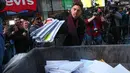 Seorang pria melempar kertas berisi kenangan menyulitkan ke tempat sampah selama kegiatan Good Riddance Day ke-13 tahunan di Times Square, New York, 28 Desember 2019. Kegiatan menjelang tahun baru tersebut menjadi tradisi untuk menghapus kenangan buruk selama satu tahun. (Kena Betancur / AFP)