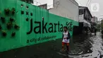 Seorang remaja melintasi banjir yang merendam lingkungan rumah tempat tinggal mereka di kawasan kecamatan Kebayoran Baru, Jakarta, Senin (25/01/2021). Hujan deras yang mengguyur Jakarta hari ini, Senin (25/1) menyebabkan terjadinya banjir di kawasan permukiman tersebut. (Liputan6.com/Johan Tallo)