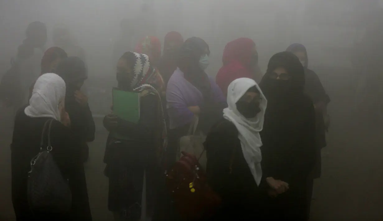 Pelajar menunggu angkutan saat kabut tebal menyelimuti Lahore, Pakistan, 15 Desember 2021. Kabut tebal membuat kendaraan harus melaju lambat karena jarak pandang berkurang. (AP Photo/K.M. Chaudary)