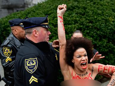 Pengunjuk rasa wanita mendatangi sidang kekerasan seksual komedian Bill Cosby di Gedung Pengadilan Montgomery, Pennsylvania, Amerika Serikat, Senin (9/4). Wanita itu ditahan karena tampil topless. (AP Photo/Corey Perrine)