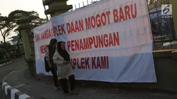 Pencari suaka melintasi spanduk penolakan di depan bekas Markas Kodim di Kalideres, Jakarta, Selasa (16/7/2019). Sejak Kamis (11/7) para pencari suaka dipindahkan dari di pinggir jalan dan trotoar di kawasan Kebon Sirih ke bekas Markas Kodim di Kalideres . (Liputan6.com/Helmi Fithriansyah)