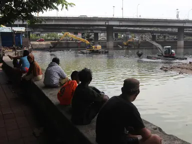 Warga menyaksikan proses pengerukan Waduk Grogol, Jakarta, Senin (9/4). Pengerukan dilakukan guna meningkatkan daya tampung waduk sebagai bagian dari upaya mengatasi banjir. (Liputan6.com/Arya Manggala)