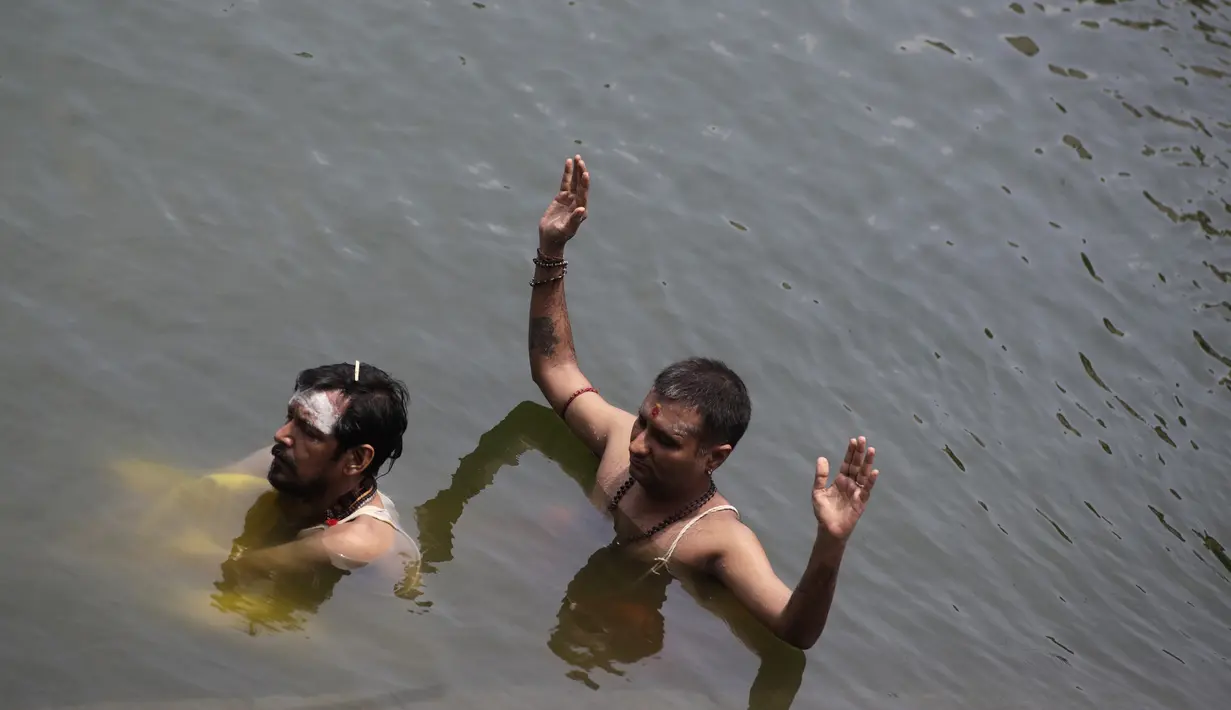 Umat Hindu duduk dalam kolam saat melakukan ritual selama gerhana matahari di Banganga, Mumbai, India, Minggu (21/6/2020). Fenomena gerhana matahari pada 21 Juni 2020 terlihat dari berbagai negara di dunia. (AP Photo/Rajanish Kakade)