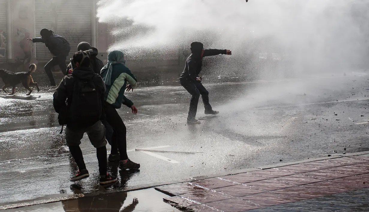 Para demonstran bentrok dengan polisi anti huru hara di sekitar Kongres di Valparaiso, Chili. Sabtu (21/5). Sejumlah gedung dibakar pengunjuk rasa saat bentrokan terjadi. (AFP Photo/Claudio Reyes)
