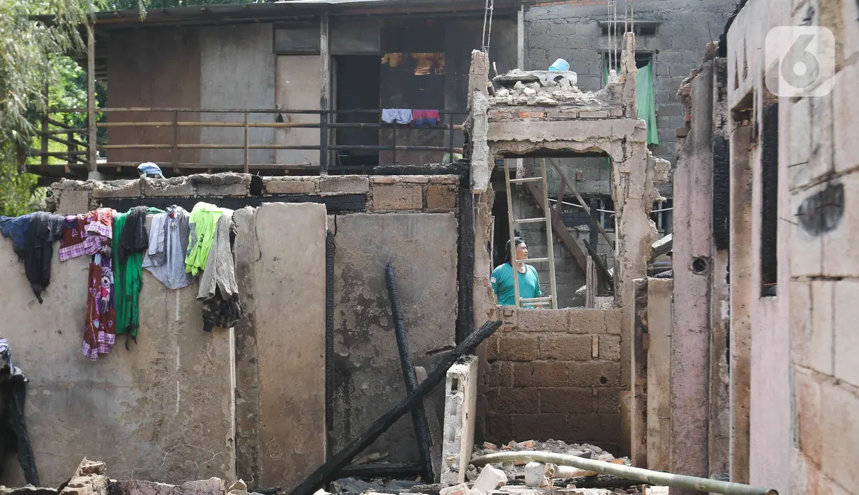 Seorang warga mencari barang-barang miliknya pasca kebakaran pemukiman di kawasan Manggarai, Jakarta, Minggu (18/12/2022). Kebakaran tersebut menghanguskan sekitar 50 rumah semi permanen yang ada di bantaran sungai Ciliwung. (Liputan6.com/Herman Zakharia)