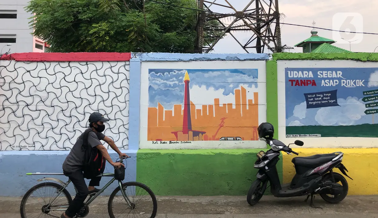 Pesepeda melintas di depan mural bertema Kota Jakarta di sekitar Rusunawa KS Tubun, Jakarta, Senin (23/11/2020). Mural tersebut dibuat guna memercantik lingkungan di sekitar rusun agar lebih berwarna dan tidak tampak kumuh. (Liputan6.com/Immanuel Antonius)