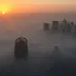 Matahari terbit memancarkan sinar yang berwarna oranye keemasan diantara gedung pencakar langit di Kota Dubai, Uni Emirat Arab, Senin (5/12). Biasanya kabut ini muncul saat musim panas yang terik berubah ke musim dingin yang cukup sejuk. (AFP/Rene Slama)