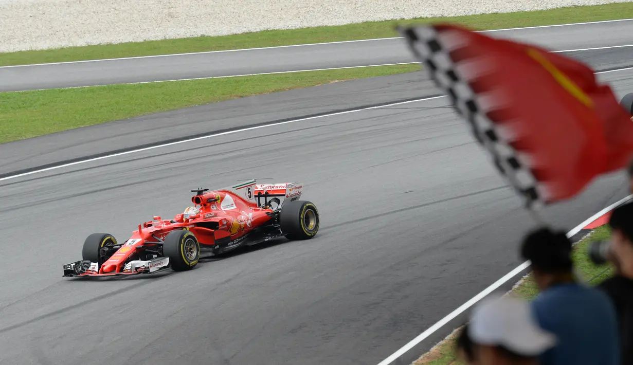 Pebalap Ferrari, Sebastian Vettel melintasi jalur dengan dukungan suporter pada balapan Formula One Malaysia Grand Prix, Sepang, (01/10/2017). Vettel akhirnya finis pada posisi keempat. (AFP/Roslan Rahman)