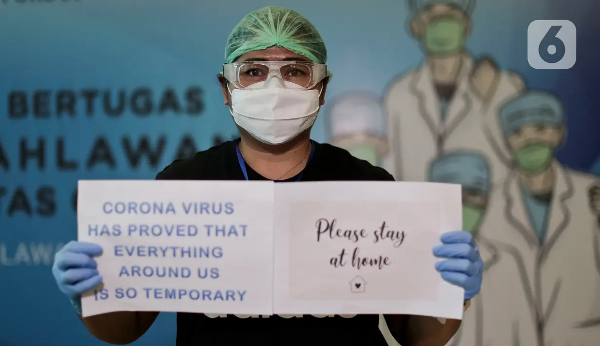 Dokter dan tenaga medis membawa tulisan berisi pesan dan tulisan untuk melawan virus corona saat sesi foto di posko tenaga medis Covid-19, Jakarta, Kamis (2/4/2020). Aksi ini mengharapkan masyarakat berdiam diri di rumah, untuk ikut bergerak memutus mata rantai covid-19. (Liputan6.com/Johan Tallo)