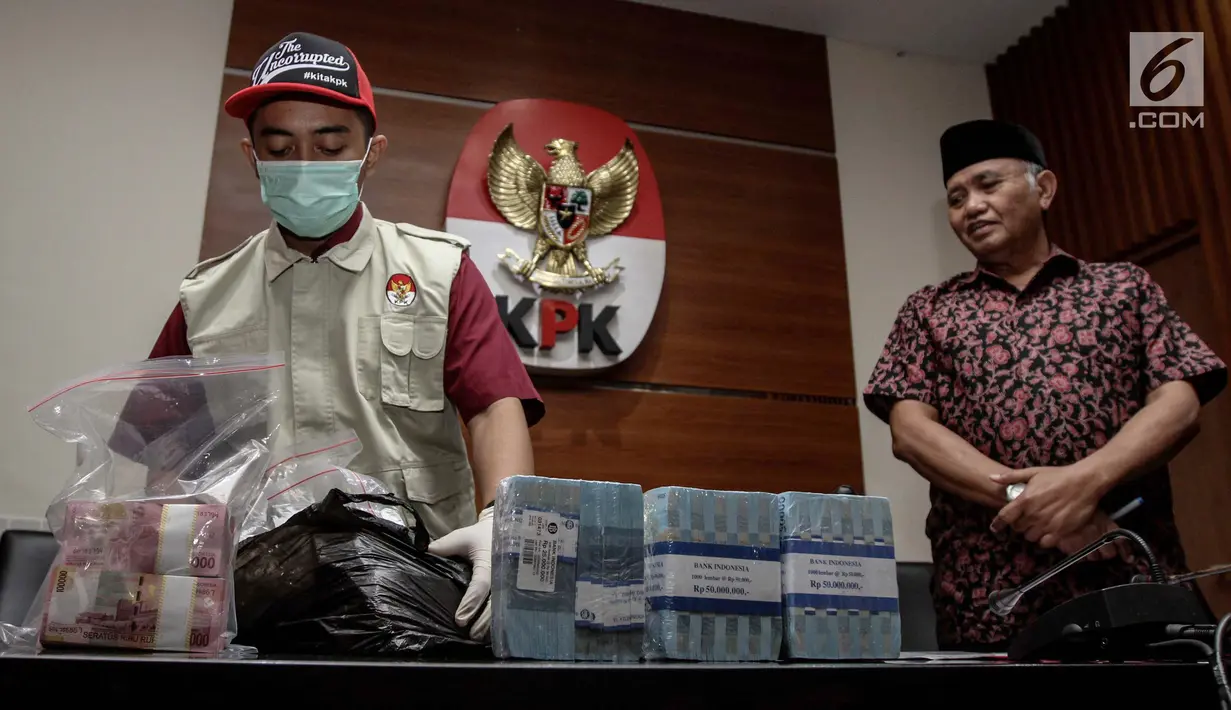 Petugas bersama Ketua KPK Agus Rahardjo (kanan) menunjukkan barang bukti hasil operasi tangkap tangan (OTT) di gedung KPK, Jakarta, Jumat (5/1). Empat tersangka tersebut salah satunya Bupati Hulu Sungai Tengah Abdul Latif. (Liputan6.com/Faizal Fanani)
