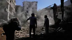 Serangan udara Israel terus menyasar wilayah Lebanon selatan dan pinggiran selatan Beirut, termasuk Jnah. Tampak dalam foto, orang-orang berkumpul saat sebuah ekskavator membersihkan puing-puing di lokasi serangan Israel pada Minggu 5 April 2026 terhadap sebuah bangunan di lingkungan Jnah, Beirut, Lebanon, Senin 6 April 2026. (AP Photo/Hassan Ammar)