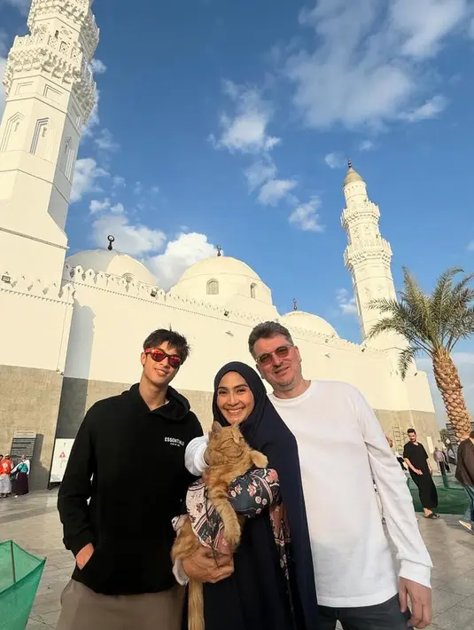 Eddy tampil mengenakan hoodie hitam dipadukan celana panjang coklat. Maudy tampak mengenakan gamis motif bunga dan kerudung panjang hitam. [@maudykoesnaedi]