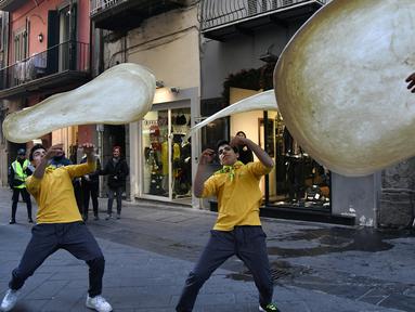 Anggota Pizzaioli Acrobats Coldiretti  melakukan Pizzaioli atau seni memutar adonan piza di Naples, Italia, 7 Desember 2017. Seni memutar adonan piza milik masyarakat Napoli reSmi masuk dalam daftar "warisan budaya tak benda" UNESCO. (Tiziana FABI/AFP)