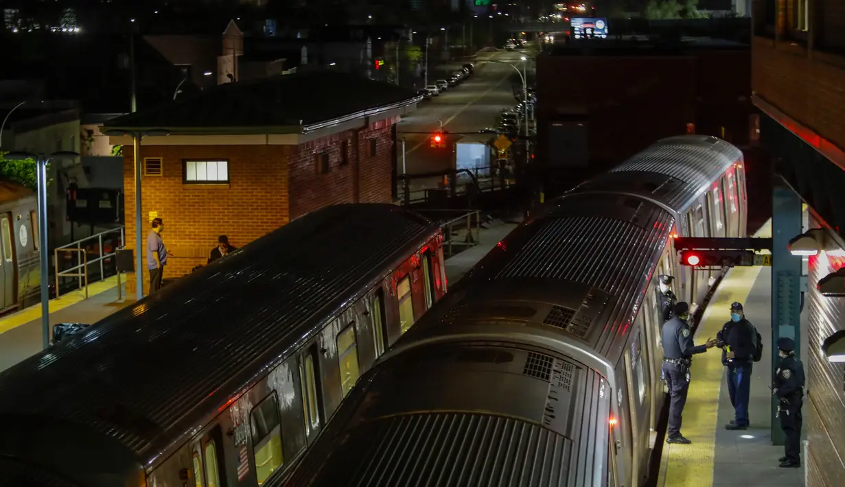 Polisi terlihat saat gerbong kereta bawah tanah dibersihkan dengan disinfektan di stasiun Coney Island di Brooklyn, Rabu (6/5/2020). Untuk pertama kalinya, sistem kereta bawah tanah New York dimatikan sementara agar dapat dibersihkan untuk menghentikan penyebaran virus corona. (AP/Frank Franklin II)