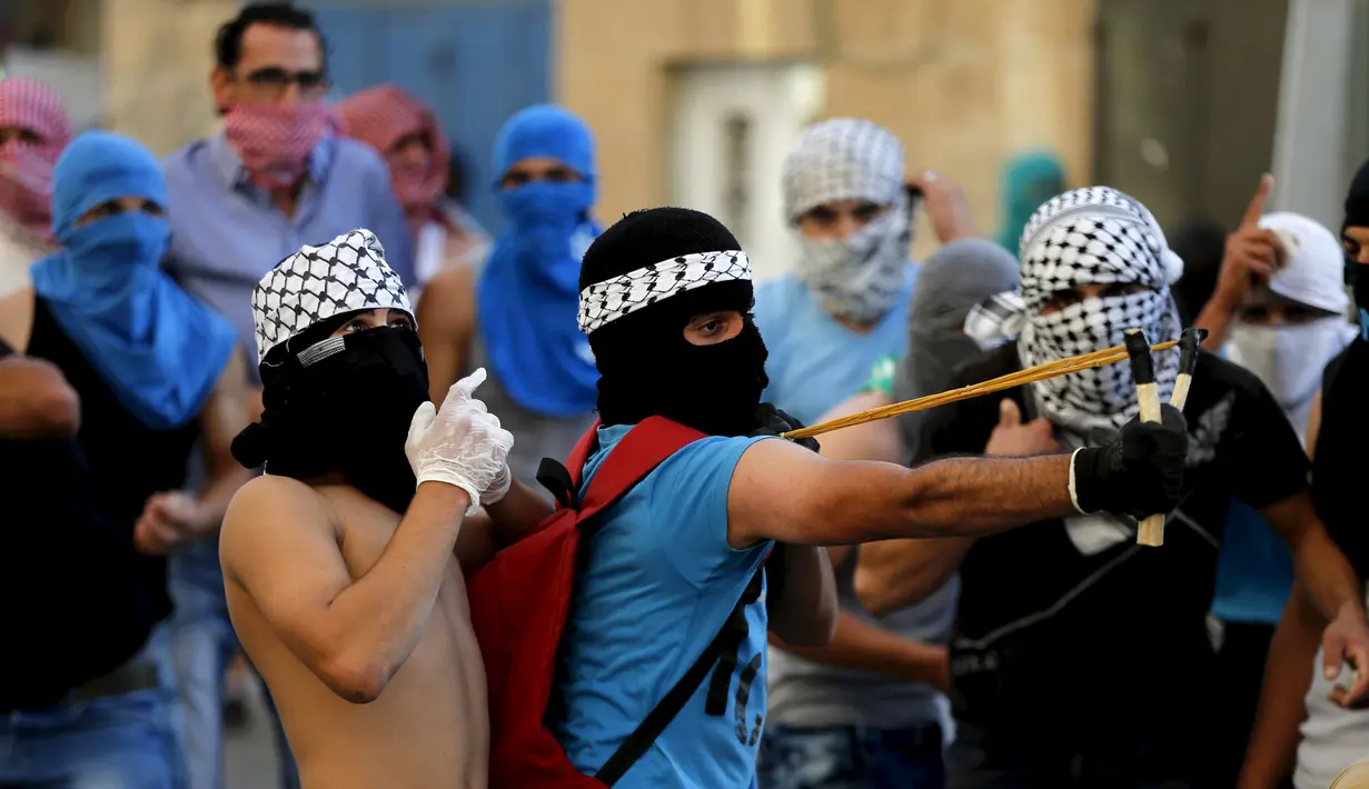 Pengunjuk rasa Palestina menggunakan ketapel untuk melempar batu ke polisi Israel dalam bentrokan di Shuafat, daerah pinggiran Arab, Yerusalem, Senin (5/10). Seorang remaja Palestina tewas pada Senin dalam bentrokan di Tepi Barat. (REUTERS/Ammar Awad) 