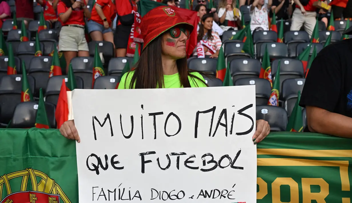 Di Timnas Portugal, Diogo Jota mencetak 14 gol dalam 49 penampilan. Ia juga merupakan salah satu suksesor dua gelar UEFA Nations League di tahun 2019 serta 2025 untuk Portugal. Tampak dalam foto, para penggemar memegang tulisan saat mereka memberikan penghormatan kepada penyerang Liverpool asal Portugal, Diogo Jota, menjelang pertandingan sepak bola UEFA Women's Euro 2025 Grup B antara Spanyol dan Portugal di stadion Wankdorf di Bern, Jerman pada 3 Juli 2025. (Miguel MEDINA/AFP)