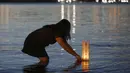 Seorang wanita meletakkan lentera kertas di atas permukaan air untuk mengenang mereka yang meninggal akibat COVID-19 di Brasilia, Brasil, 30 November 2020. Kematian akibat COVID-19 di Brasil menjadi 173.120 kasus. (Xinhua/Lucio Tavora)