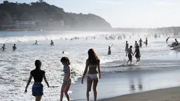 Orang-orang menikmati pantai di dekat Pulau Enoshima di Prefektur Kanagawa, barat daya Tokyo, (13/8/2019). Secara administratif, Enoshima adalah bagian dari kota daratan Fujisawa, dan terhubung ke bagian Katase di kota itu dengan jembatan sepanjang 2.000 meter. (AFP Photo/Charly Triballeau)